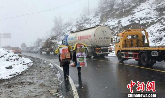 因大雪导致国道318线折多山路段封路，民众徒步给受困驾乘人员送食品上山。 甘孜交警供图